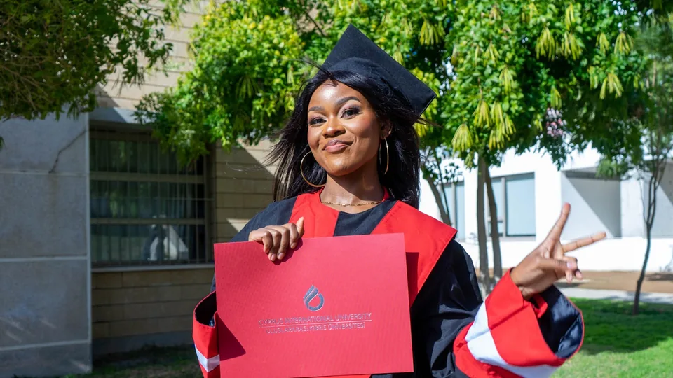 Jeune diplômée en toge présentant fièrement son diplôme