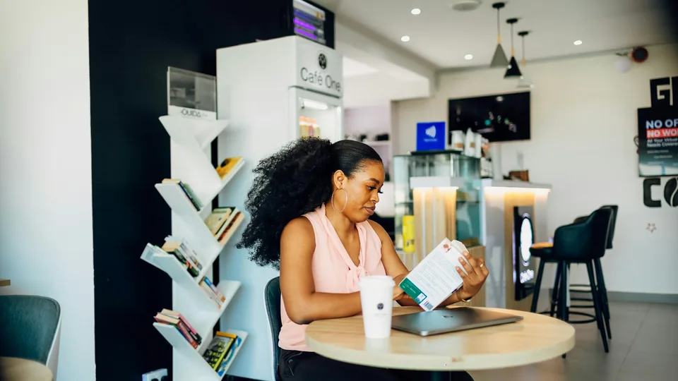 Jeune femme ouvrant un compte en ligne sur son ordinateur portable, carte bancaire en main